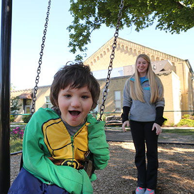 A child on a swing with a person behind him