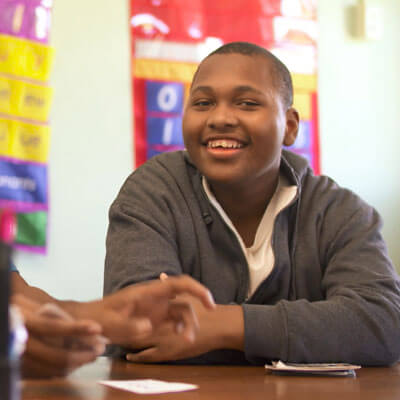 A child sitting at a table smiling.