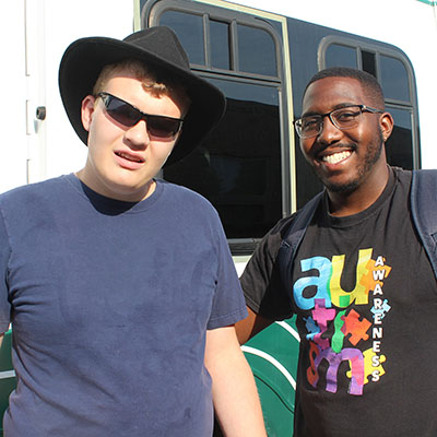 two men standing next to a bus