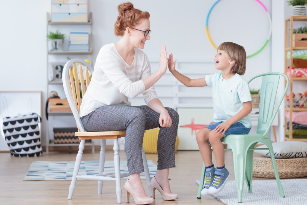 therapist giving child with autism high five during ABA therapy session