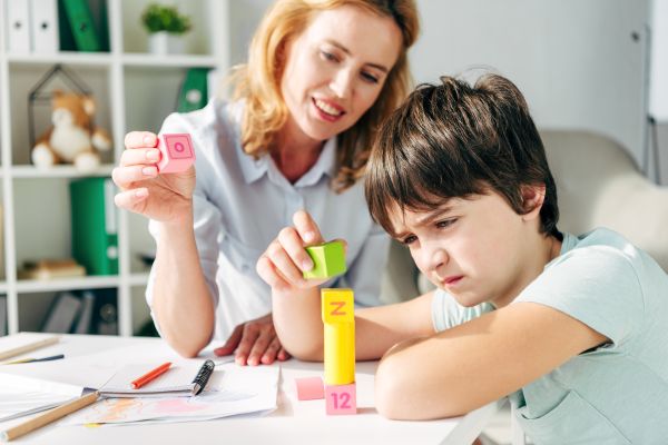 child with autism engaging in play therapy with teacher