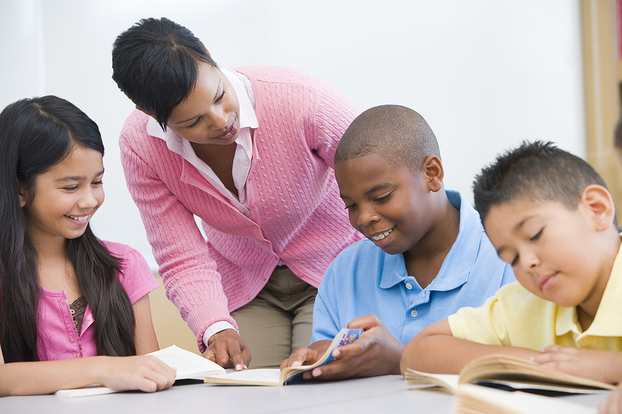 A teacher helping students read a book