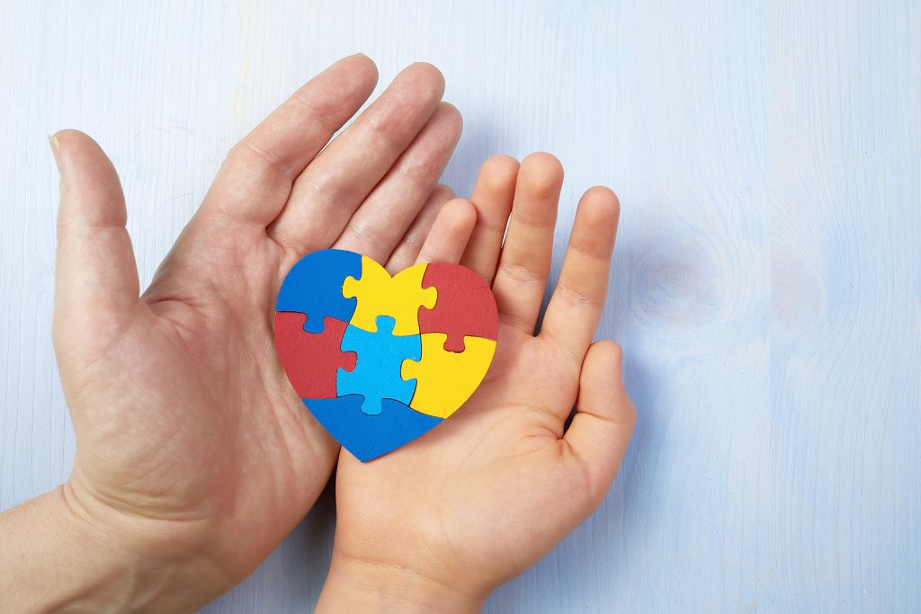 Parent and child holding autism awareness puzzle piece in their hands.