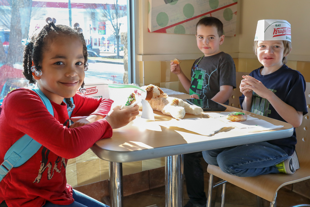 A group of kids sitting at a table having snacks