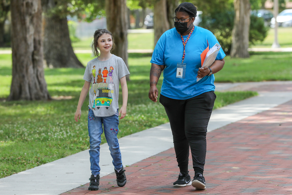 A person and a child walking on a sidewalk