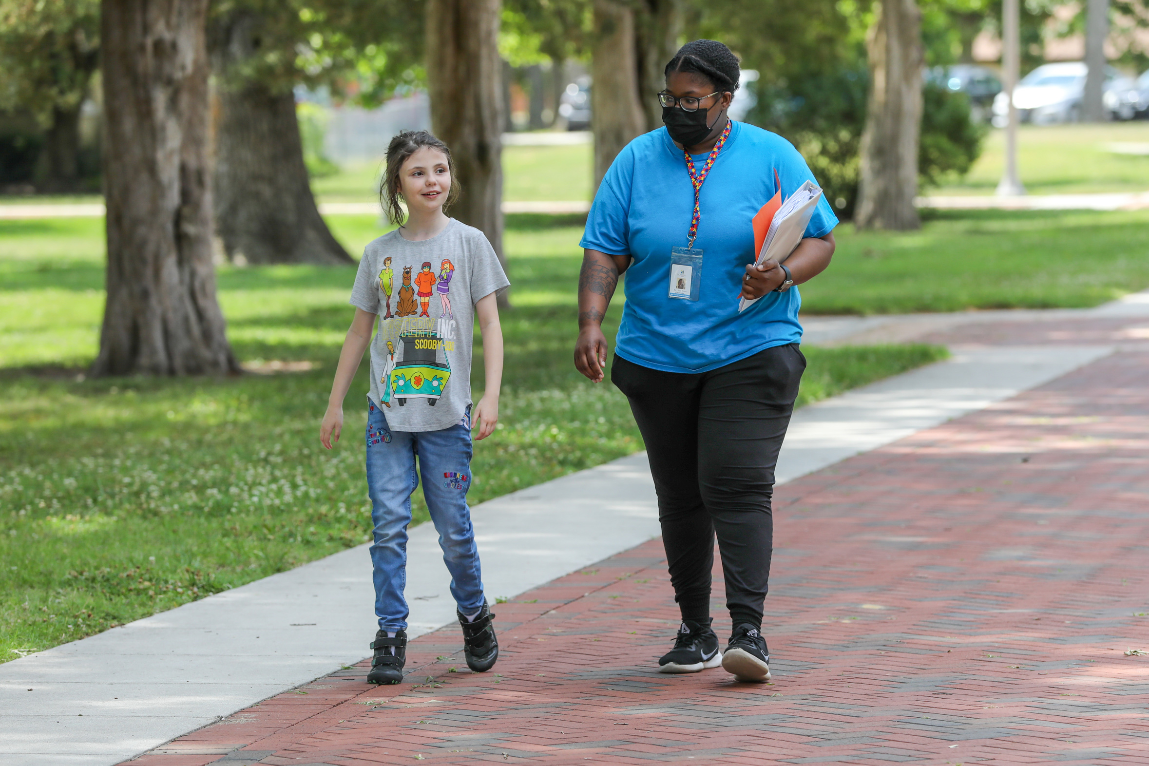 A person and a child walking on a sidewalk